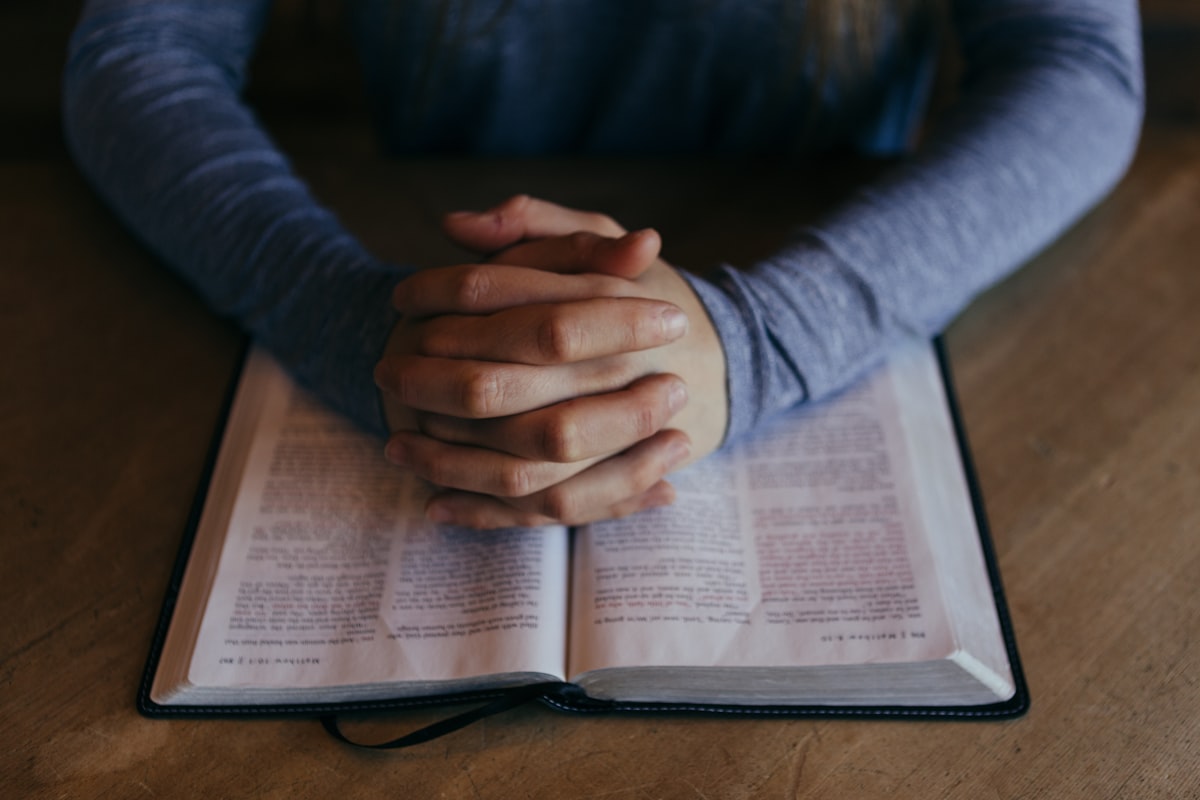 Hands in prayer over scripture